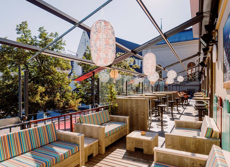 Sonnige Papa Joe's Terrasse mit Lounge Breich und Stehtischen in schöner Holzoptik - Urlaubsfeeling inklusive